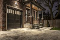 a brown brick building with a black front door and black trimmings and three garage doors
