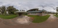 the view of a house with large grass and trees near it as a fish eye lens