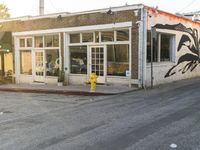 a yellow fire hydrant on the side of the road with the sun shining in front of a store front