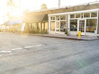 a yellow fire hydrant on the side of the road with the sun shining in front of a store front