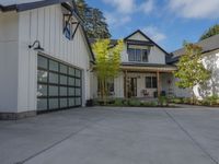 two houses with large glass doors in front of the garage door and the street is lined with trees