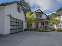 two houses with large glass doors in front of the garage door and the street is lined with trees