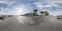 fish eye lens photograph of a road with vehicles on it and some houses in the background