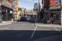 a small street has been paved with many shops and buildings on both sides with cars parked