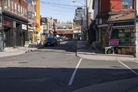 a small street has been paved with many shops and buildings on both sides with cars parked