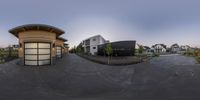 a fisheye view of a small building and street in a suburb at sunset, with people walking by