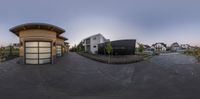 a fisheye view of a small building and street in a suburb at sunset, with people walking by