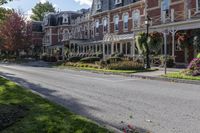 a street lined with parked cars near a tall brick building and lawn area with colorful flowers in the foreground