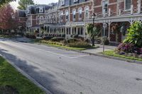 a street lined with parked cars near a tall brick building and lawn area with colorful flowers in the foreground