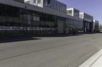 a fire hydrant is near an empty street outside an industrial building in the middle of an urban setting