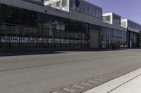 a fire hydrant is near an empty street outside an industrial building in the middle of an urban setting