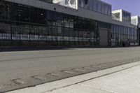 a fire hydrant is near an empty street outside an industrial building in the middle of an urban setting