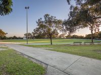 this is a park with a large grassy area with trees, benches and several lights