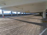 an empty parking garage that has only a few cars to be seen in it and a view of a building behind