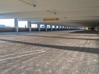 an empty parking garage that has only a few cars to be seen in it and a view of a building behind