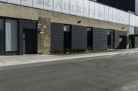 a motorcycle rider travels past a large building in a parking lot, with the city in the background