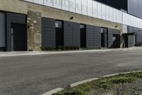 a motorcycle rider travels past a large building in a parking lot, with the city in the background