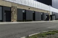 a motorcycle rider travels past a large building in a parking lot, with the city in the background