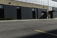 a motorcycle rider travels past a large building in a parking lot, with the city in the background