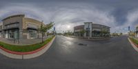 an asphalt street with a shopping center and a cloudy sky overhead at the camera taken from the same angle