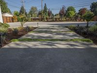 a paved concrete walkway leads down to the parking lot with trees and plants growing behind it