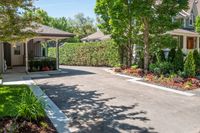 driveway in a residential area with trees and plants, shrubs and landscaping on either side