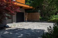 the driveway has some stone on it next to trees and bushes on the sidewalk of this home