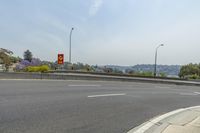 street signs sit next to a highway with trees in the distance and a hillside in the distance