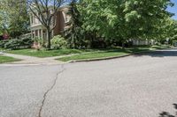 residential street with houses on one corner and trees to the other side of a road