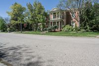 residential street with houses on one corner and trees to the other side of a road