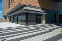 a person walking across an empty street in front of a brick building with two bikes parked on the sidewalk