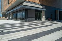 a person walking across an empty street in front of a brick building with two bikes parked on the sidewalk