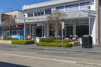 a few people are sitting on a bench outside a restaurant near the road, waiting for people to eat