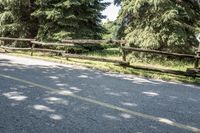 a person on a bike rides along a road near an old wooden fence, which is made of logs and sticks