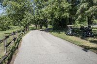 two golf carts with three carts and two people riding on one bike down a road