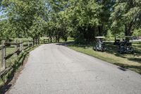 two golf carts with three carts and two people riding on one bike down a road