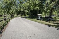 two golf carts with three carts and two people riding on one bike down a road