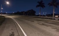 two streetlights shine above the empty road in the dark sky behind the cars driving down it