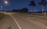 two streetlights shine above the empty road in the dark sky behind the cars driving down it