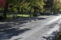 empty street next to some park bench and benches in the middle of a green area