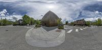 the view is distorted in a fisheye lens on a street corner with houses, trees, and buildings