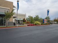 a street scene with empty parking space on either side of the road and flags on both sides