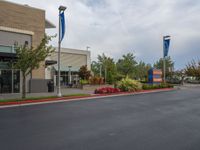 a street scene with empty parking space on either side of the road and flags on both sides