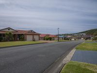 a street with houses on it and grass surrounding it and in the foreground is an empty road and houses