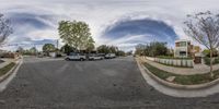 two cars driving down a street with houses in the background, a street scene is shown through a fisheye lens