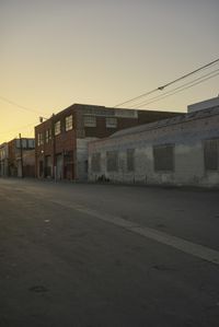 a street with a car on it at sunset in front of some large building with lots of windows