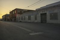 a street with a car on it at sunset in front of some large building with lots of windows