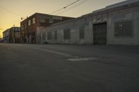 a street with a car on it at sunset in front of some large building with lots of windows