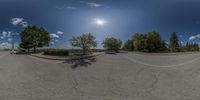 a group of cars parked on the side of a street near trees and grass as if it were a fish eye lens