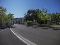 an empty street with trees in the middle of it and a fence surrounding the road